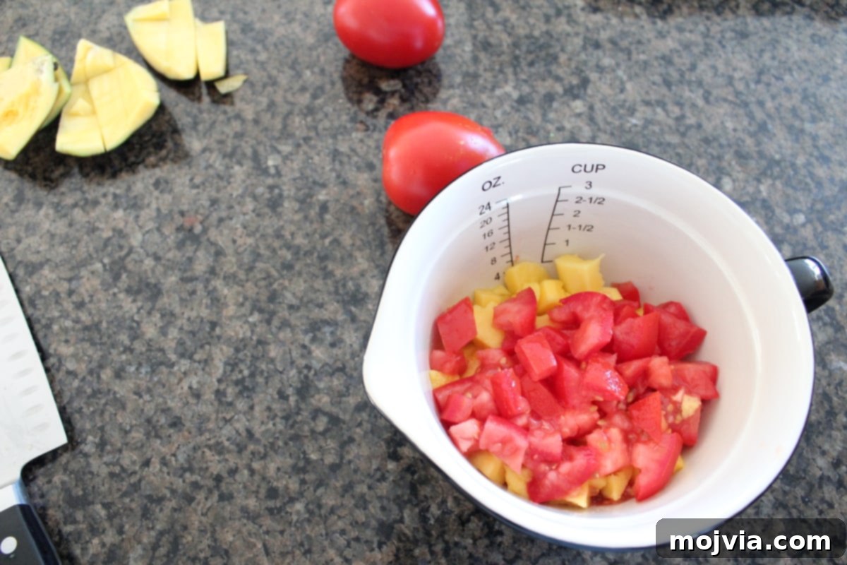Fresh Mango Salsa 2 Diced mango and tomatoes in a white bowl, the first step in making fresh mango salsa.