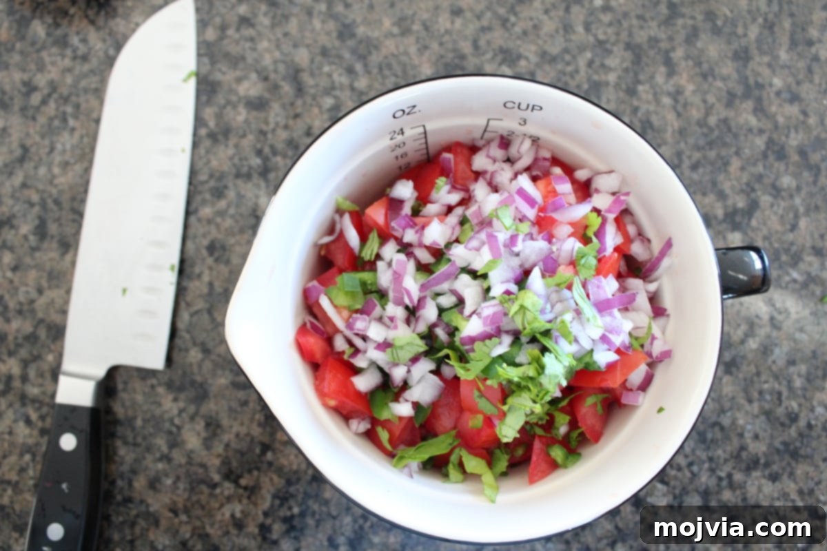 Fresh Mango Salsa 3 Finely minced red onion, jalapeño, and chopped cilantro added to a bowl with mango and tomatoes, preparing for the final mix.