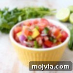 Toss this easy, homemade Tomato Mango Salsa recipe together in 5 minutes to serve on top of fresh fish, tacos or with chips for dipping!