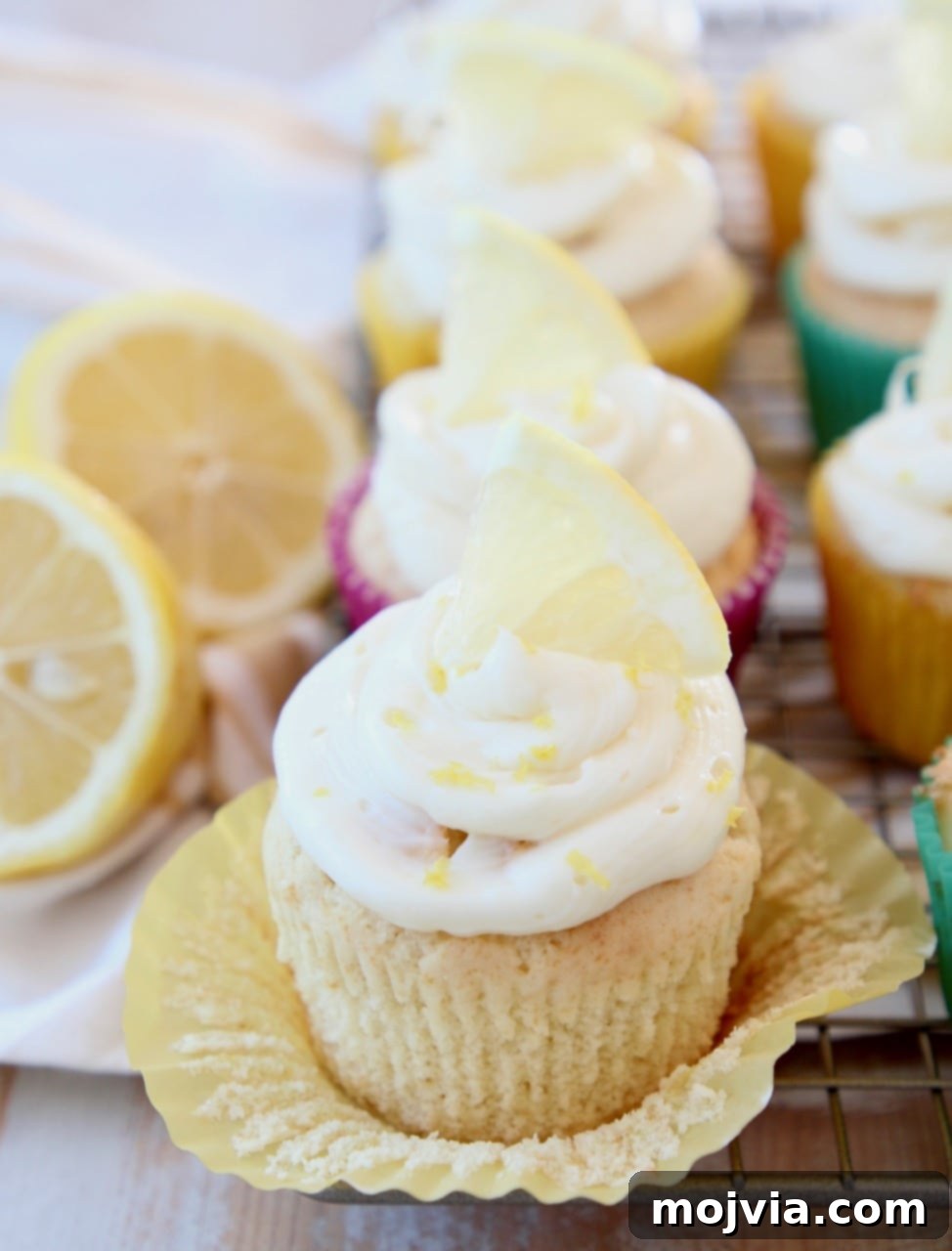 Zesty Lemon Buttercream Cupcakes 5 Lemon cupcake with wrapper unfolded, topped with lemon cream cheese frosting and lemon wedge