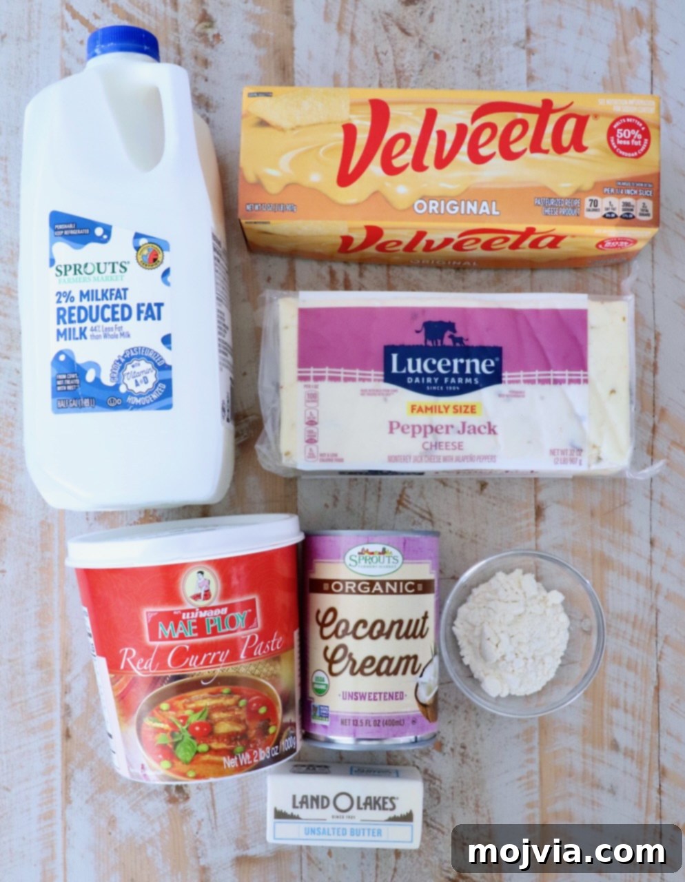 Curried Cheese Dip 3 A flat lay of ingredients including milk, Velveeta cheese, pepper jack cheese, red curry paste, coconut cream, flour, and butter.