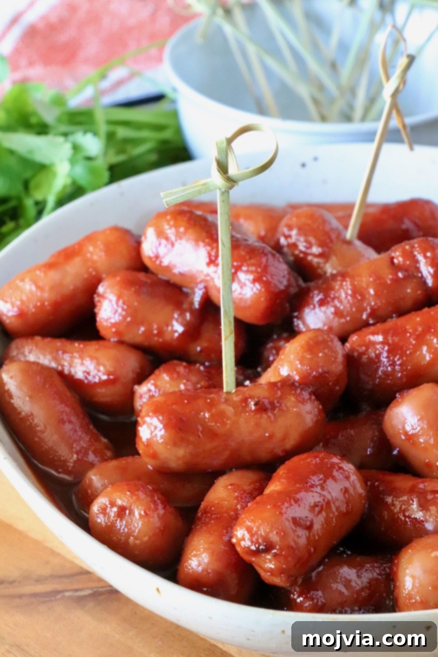 Chipotle Honey Glazed Cocktail Smokies 2 Glazed cocktail sausages in a white bowl with toothpicks