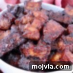 Crispy Air Fryer Pork Belly Bites 7 Close-up of glazed, caramelized pork belly bites in a white bowl