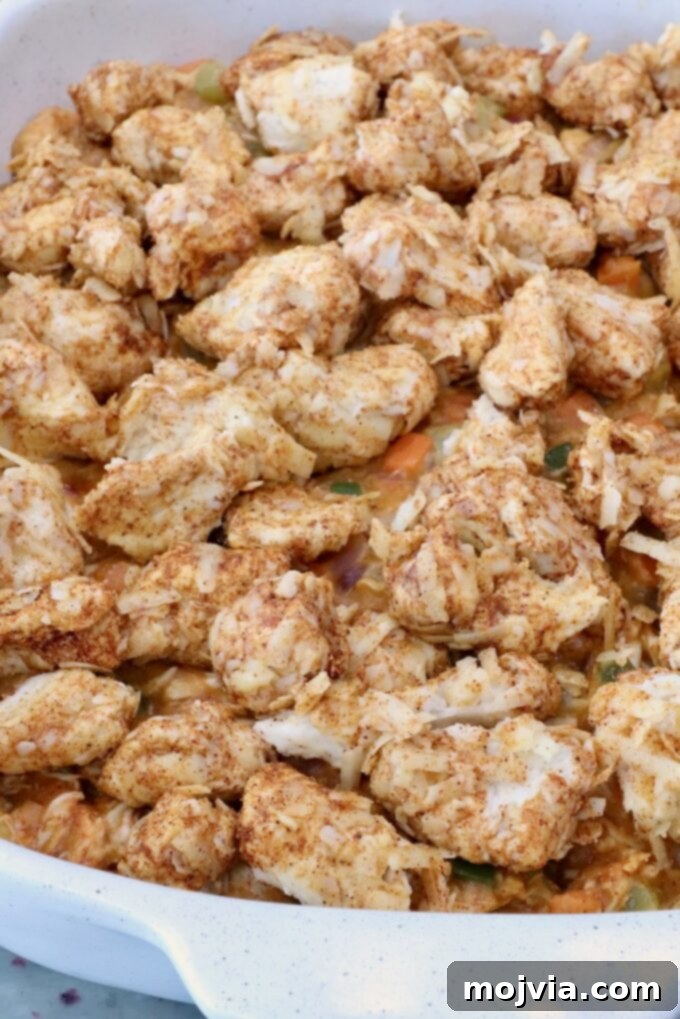 seasoned cubes of biscuit dough on top of pot pie filling in a baking dish