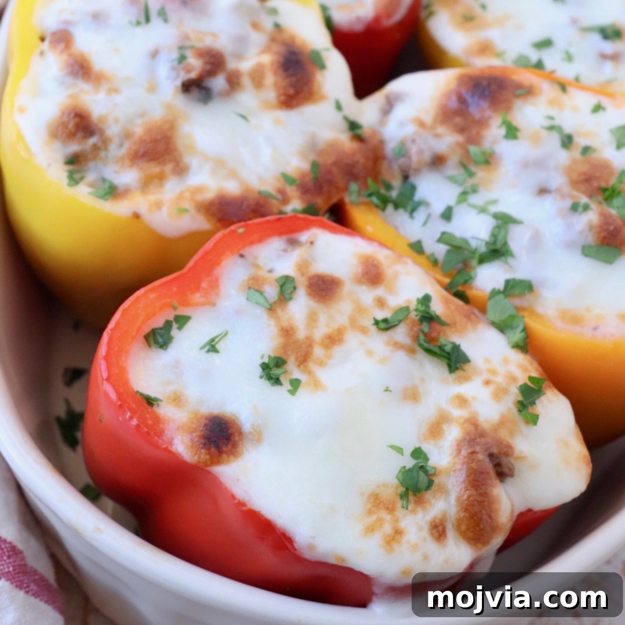 stuffed peppers topped with melted mozzarella cheese in casserole dish