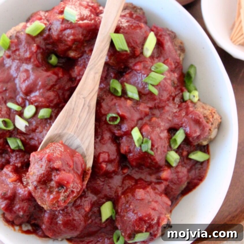 bbq meatballs in bowl with wooden spoon topped with diced green onions