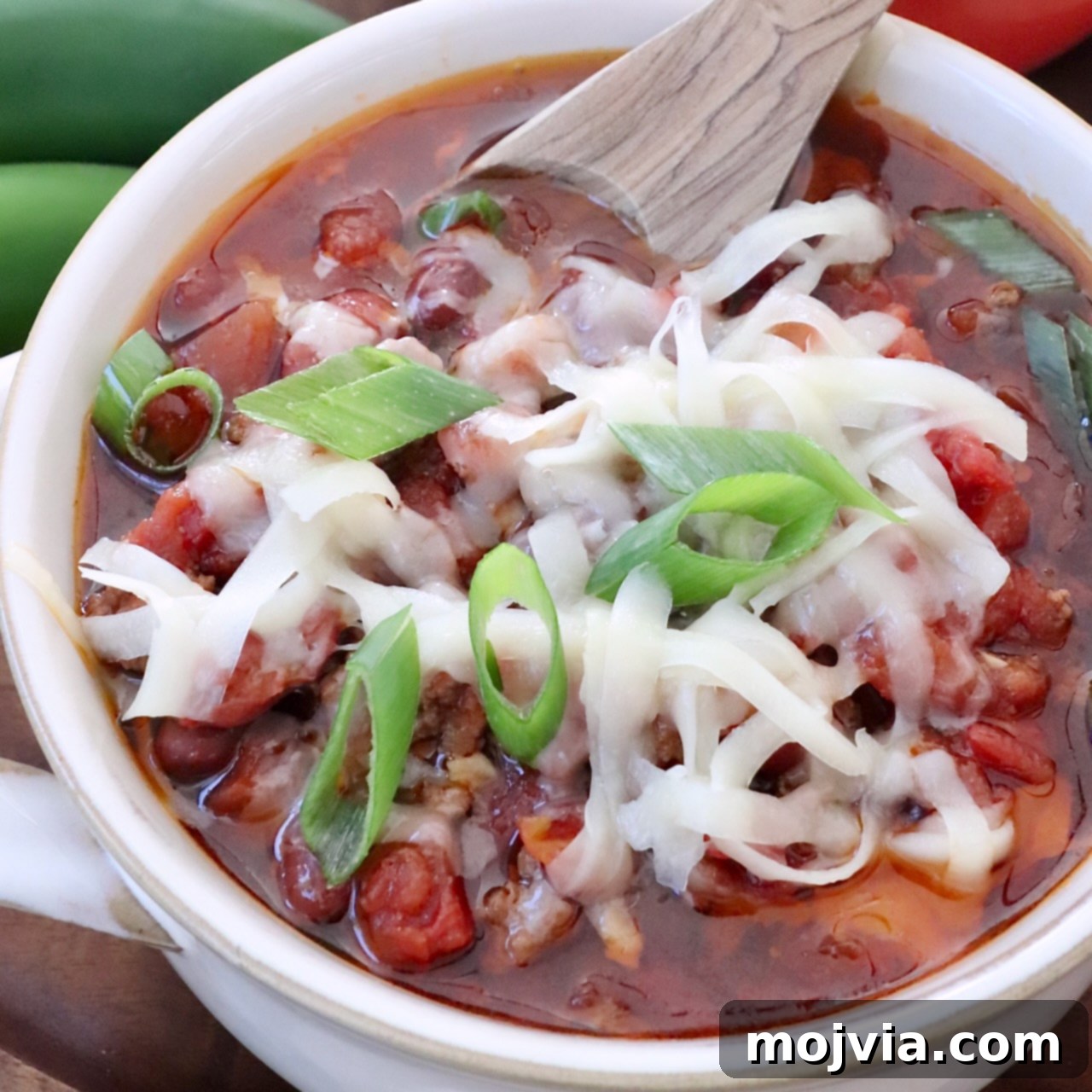 chili in a bowl with a spoon topped with grated cheese