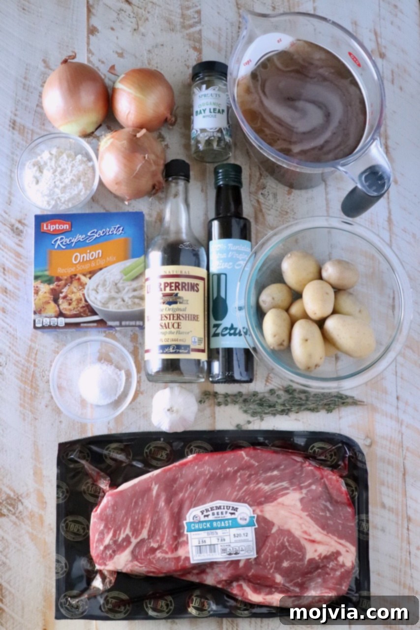 Caramelized Onion Beef Braise 3 Overhead view of beef stew ingredients on a wooden surface: chuck roast, potatoes, onions, garlic, broth, Worcestershire sauce, olive oil, bay leaves, and seasonings.