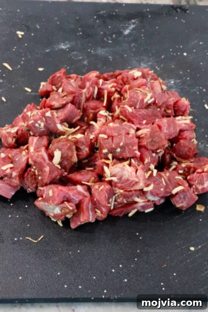 Caramelized Onion Beef Braise 5 cubes of beef tossed with french onion seasoning on a black cutting board