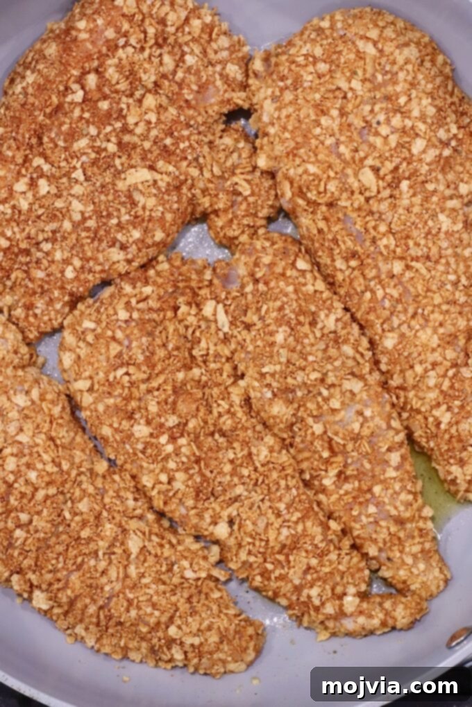 Fiesta Chicken Parmesan 6 Four golden-brown, tortilla chip crumb-coated chicken breasts sizzle in a skillet.