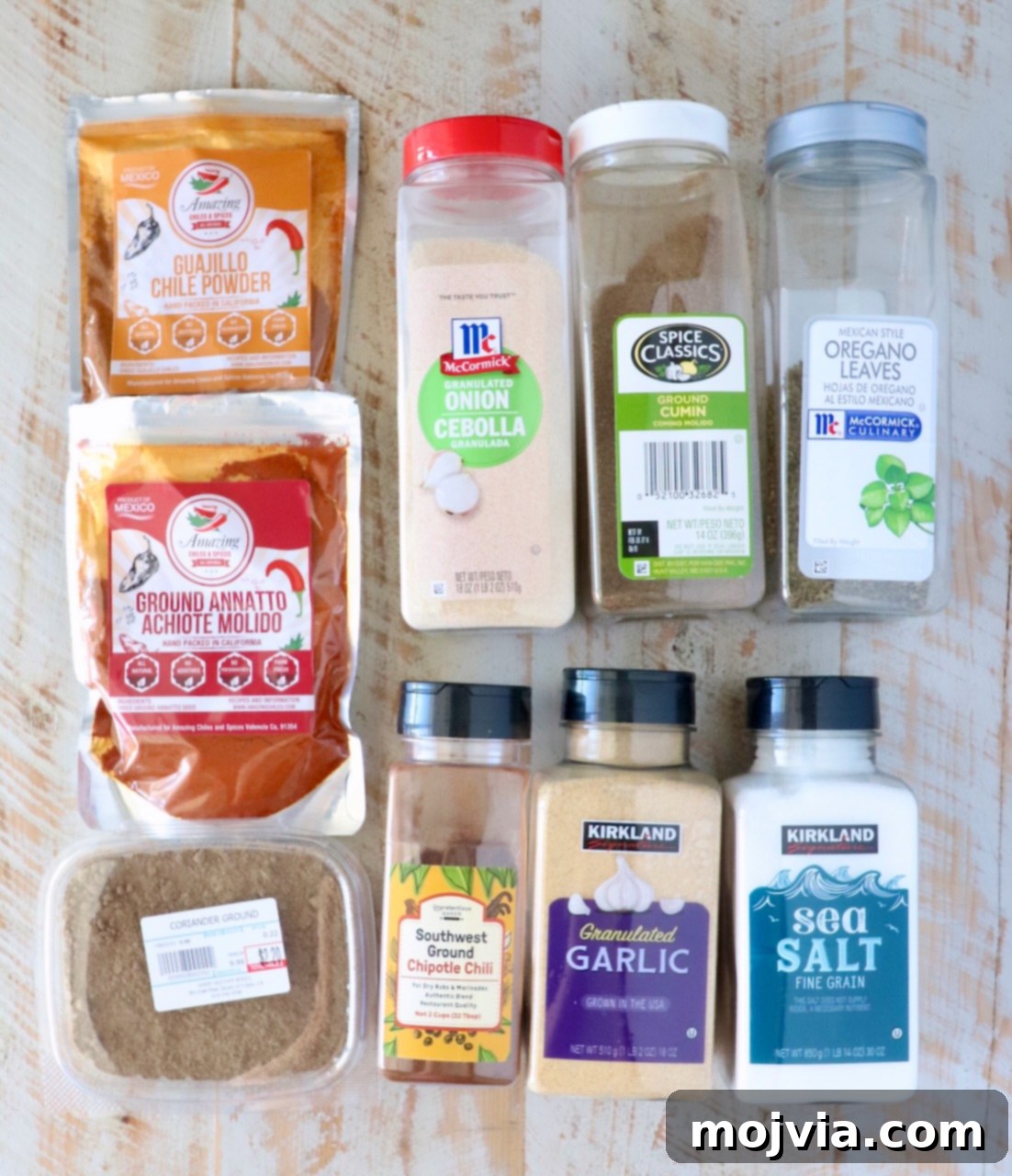 Mexican Street Taco Al Pastor Blend 3 A variety of seasoning packages are arranged on a wooden surface, featuring chili powders, granulated onion, cumin, oregano, garlic, sea salt, and more.