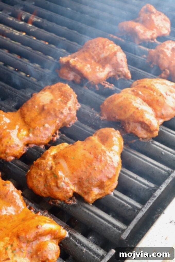 Vibrant Al Pastor Chicken 4 Marinated chicken thighs laid out on a hot grill, starting to cook and develop char marks.