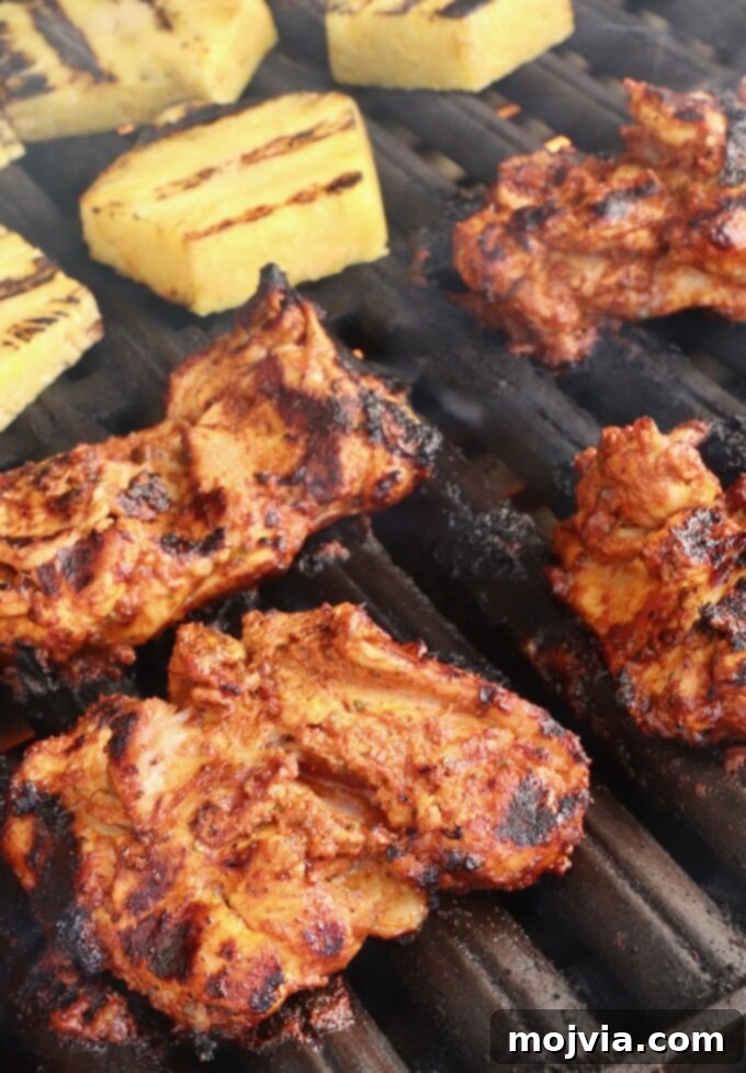 Vibrant Al Pastor Chicken 5 Grilled marinated chicken thighs alongside slices of fresh pineapple on a grill, both cooking to perfection.