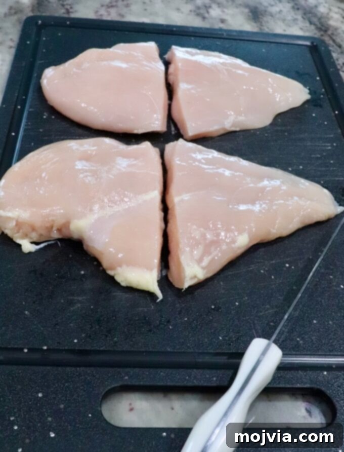 Crispy Air-Fried Chicken Sandwich 5 chicken breasts cut in half on a cutting board, sitting next to a knife