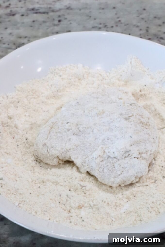 Crispy Air-Fried Chicken Sandwich 9 a piece of coated chicken in a bowl of flour