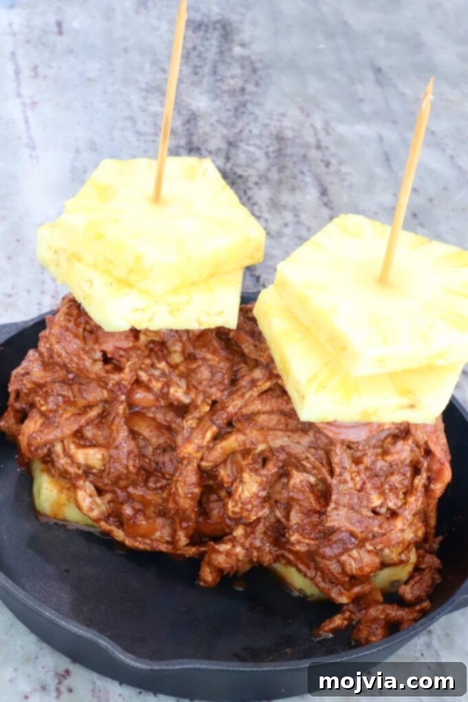 Sweet & Spicy Al Pastor Pork 5 thinly sliced marinated pork stacked up on skewers with pineapple slices in a cast iron skillet