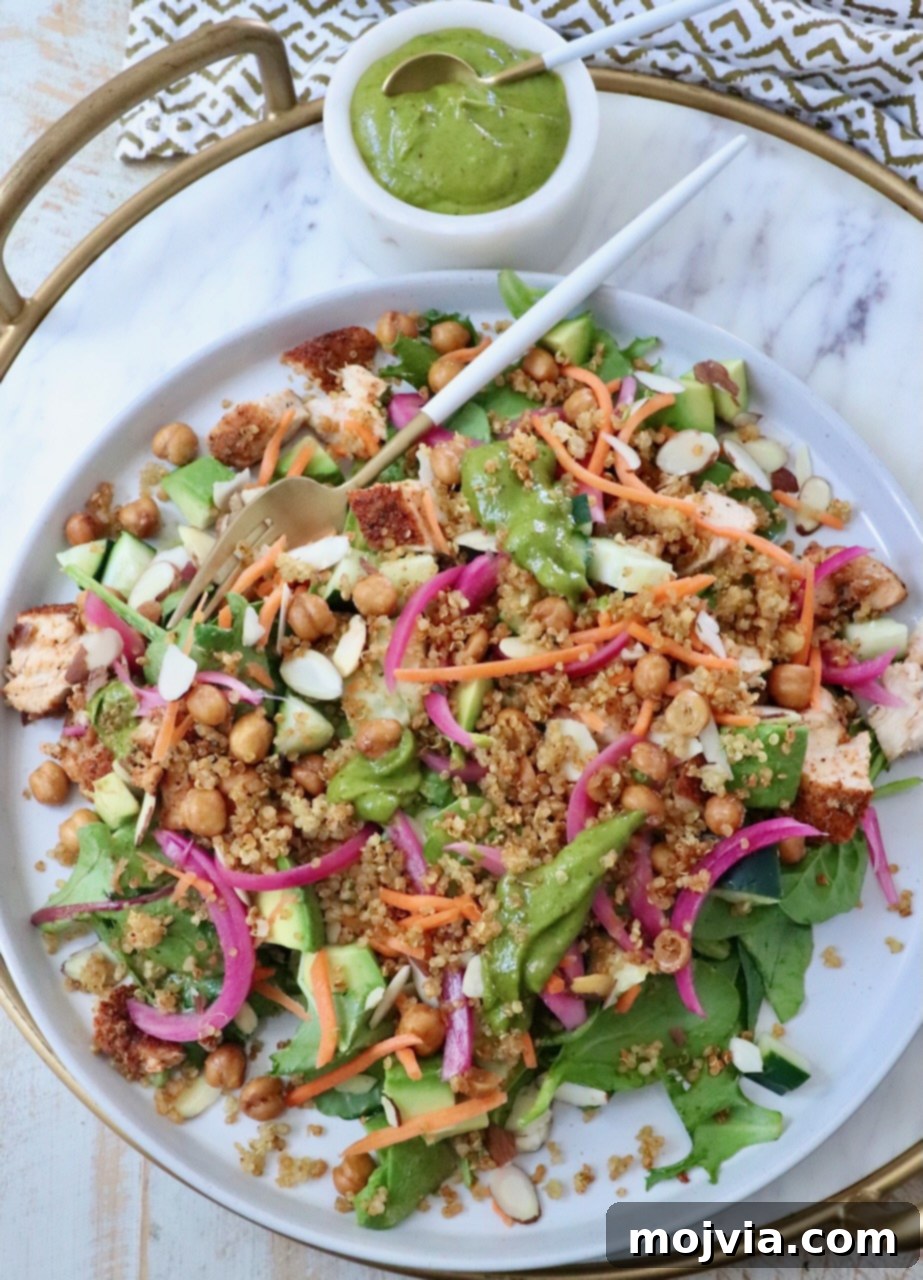 Bayou Blackened Chicken Salad 2 A vibrant Blackened Chicken Salad with greens, crispy quinoa, spiced chickpeas, sliced almonds, shredded carrots, and tangy pickled onions, artfully arranged on a platter.