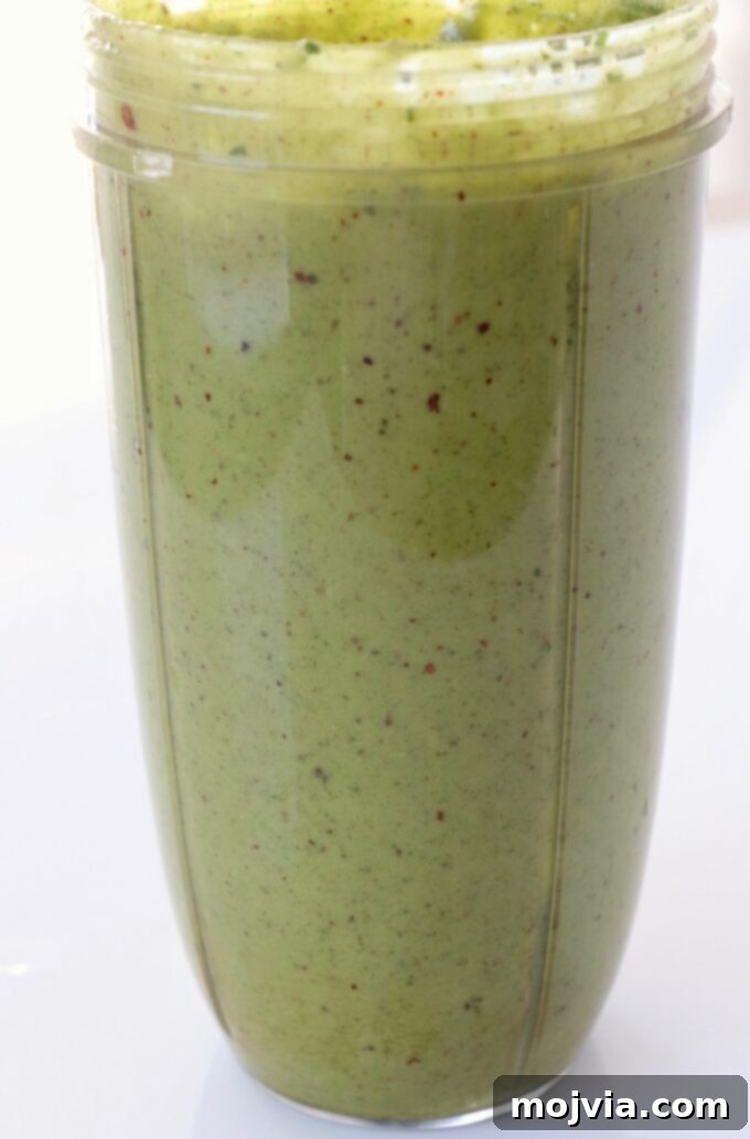 Bayou Blackened Chicken Salad 6 Vibrant spicy cashew dressing being blended to a smooth, creamy consistency in a blender cup.