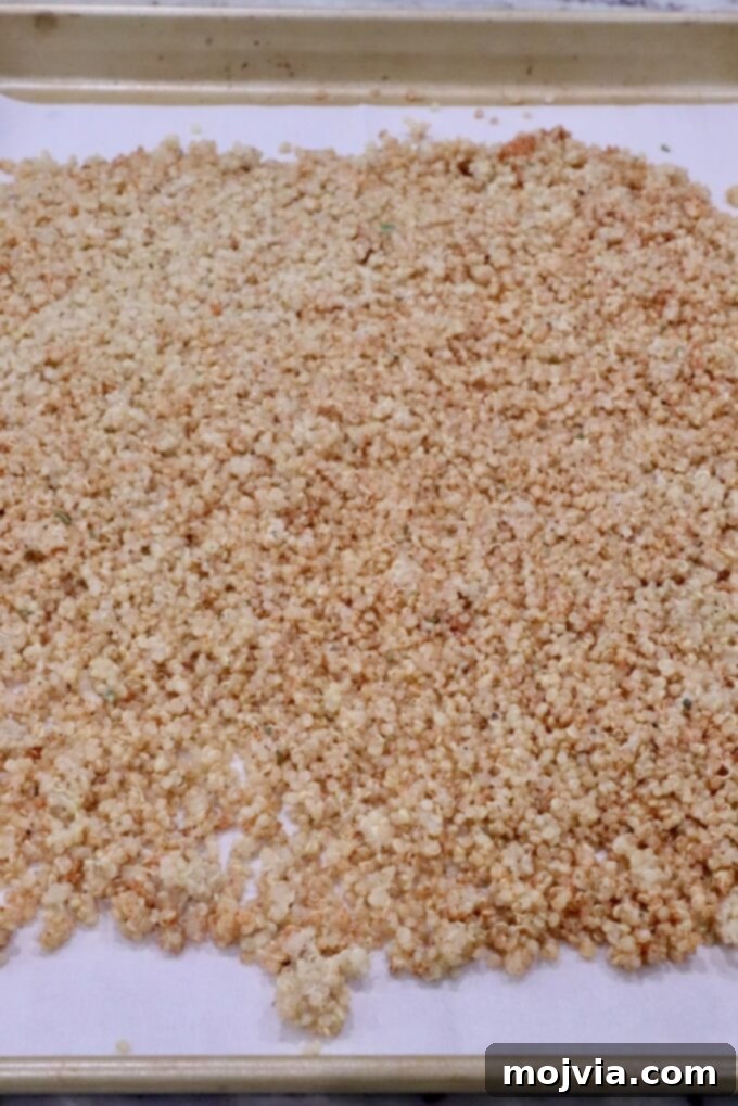 Bayou Blackened Chicken Salad 9 Seasoned, cooked quinoa spread across a parchment-lined baking sheet, prepared for roasting to achieve perfect crispiness.