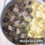 meatballs au poivre in a skillet with cooked egg noodles