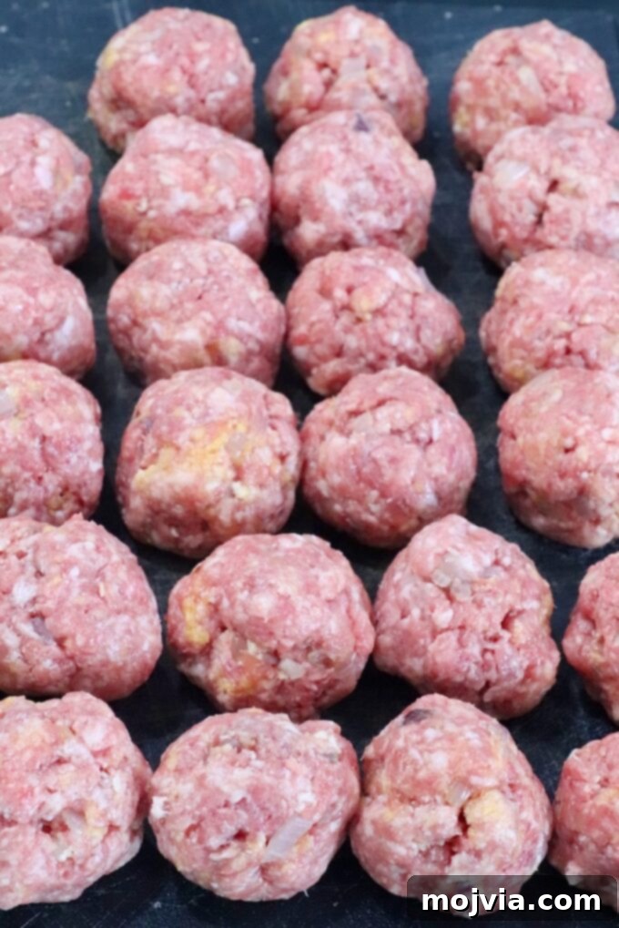 Creamy Peppercorn Meatballs 4 raw meatballs on a dark cutting board