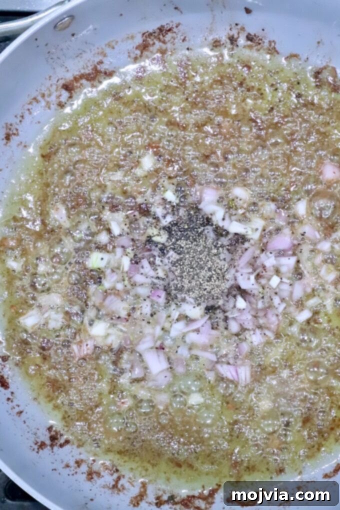 Creamy Peppercorn Meatballs 8 shallots and black pepper in liquid in a skillet