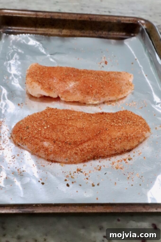 seasoned raw chicken breasts on a foil-lined baking sheet