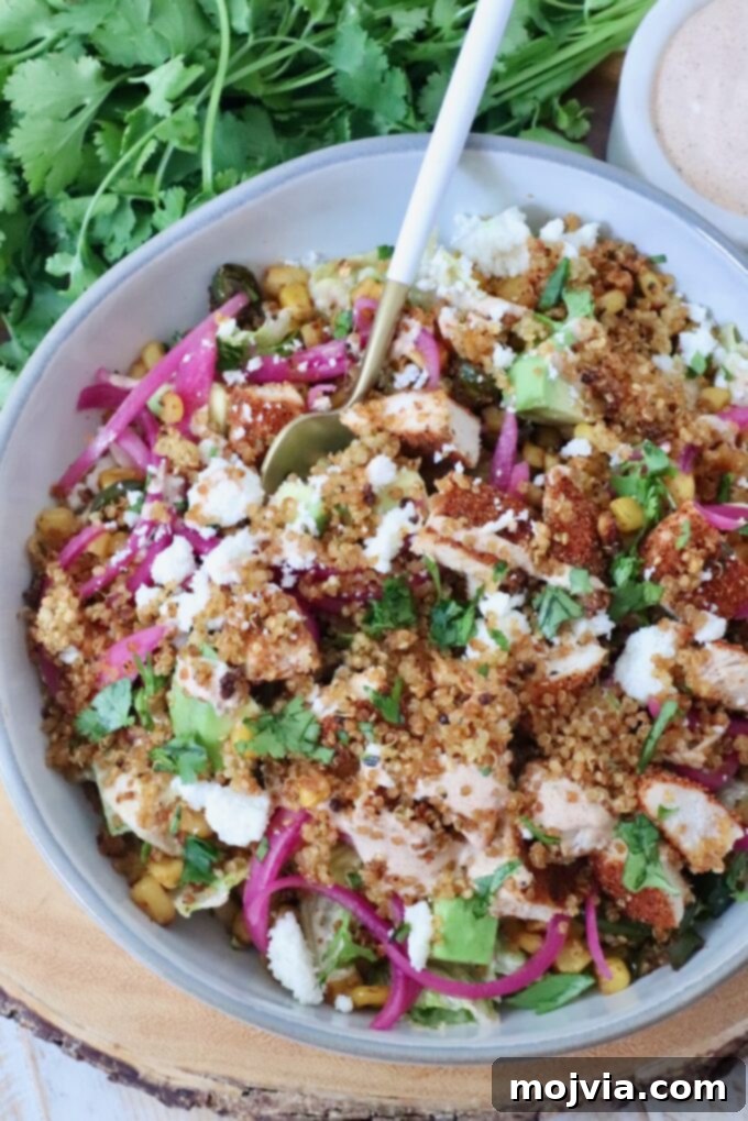 Golden Quinoa Crunch 7 A vibrant Mexican street corn chicken bowl featuring crispy quinoa, grilled chicken, fresh avocado, sweet corn, tangy pickled onions, and crumbled cheese.