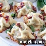 Thai Basil Chicken Dumplings: Flavorful Asian-Style Potstickers 13 Thai basil chicken dumplings on a plate topped with chili crisp and thai basil leaves