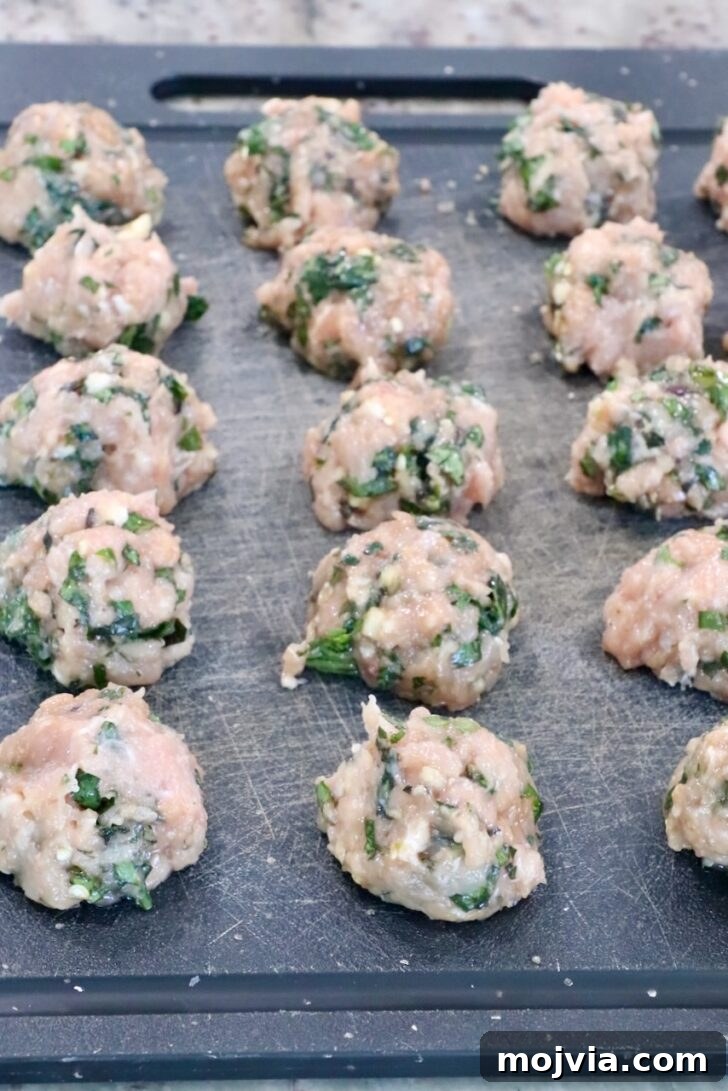 Thai Basil Chicken Dumplings: Flavorful Asian-Style Potstickers 8 raw Thai basil chicken meatballs on a black cutting board