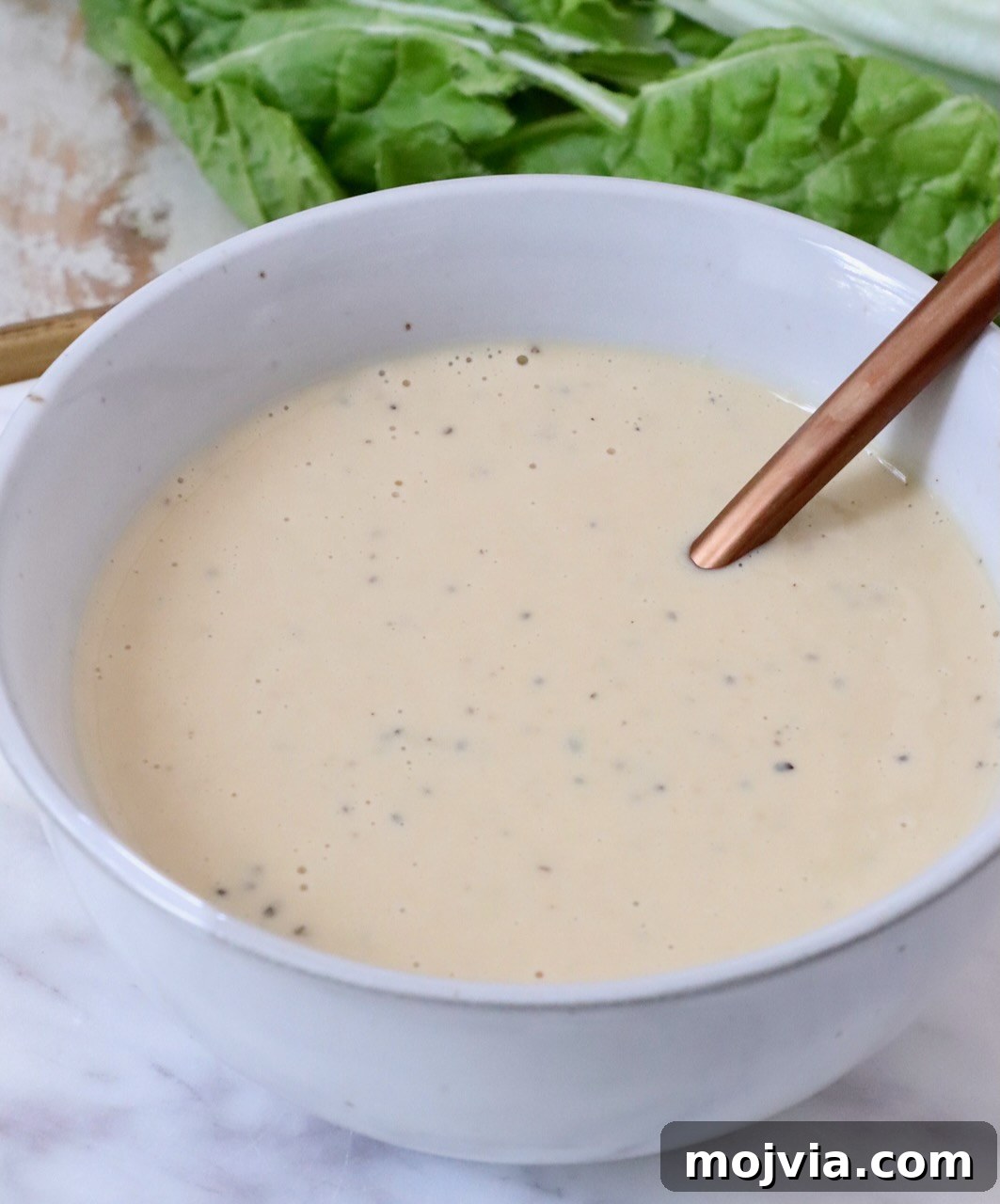 Miso Caesar Dressing Recipe: Creamy Umami Salad Dressing 2 miso caesar dressing in a bowl with lettuce sitting behind the bowl
