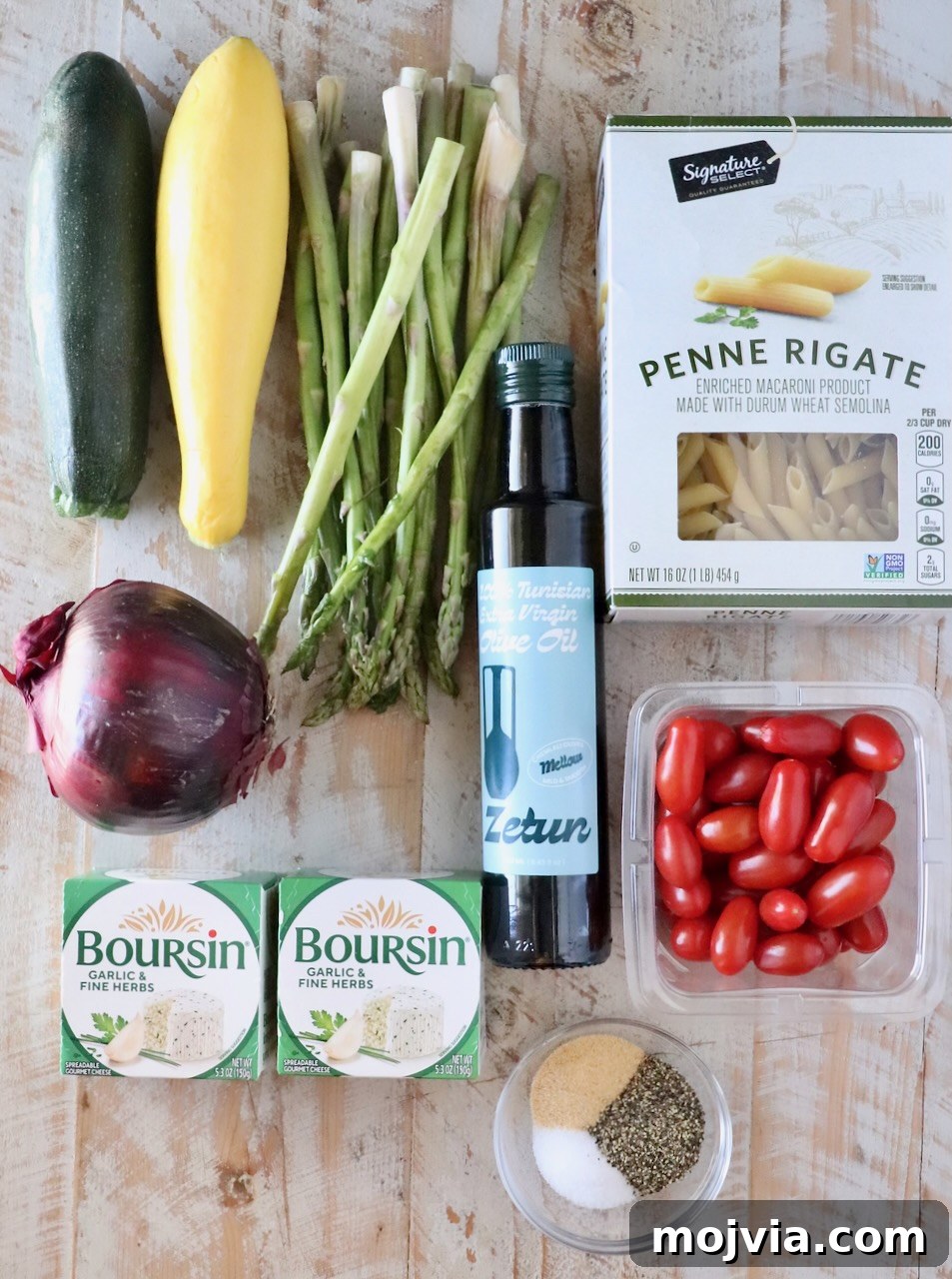 Creamy Boursin Pasta Primavera with Spring Vegetables 5 Assorted fresh ingredients on a wooden surface: zucchini, yellow squash, asparagus, red onion, cherry tomatoes, penne pasta, olive oil, Boursin cheese, and spices.