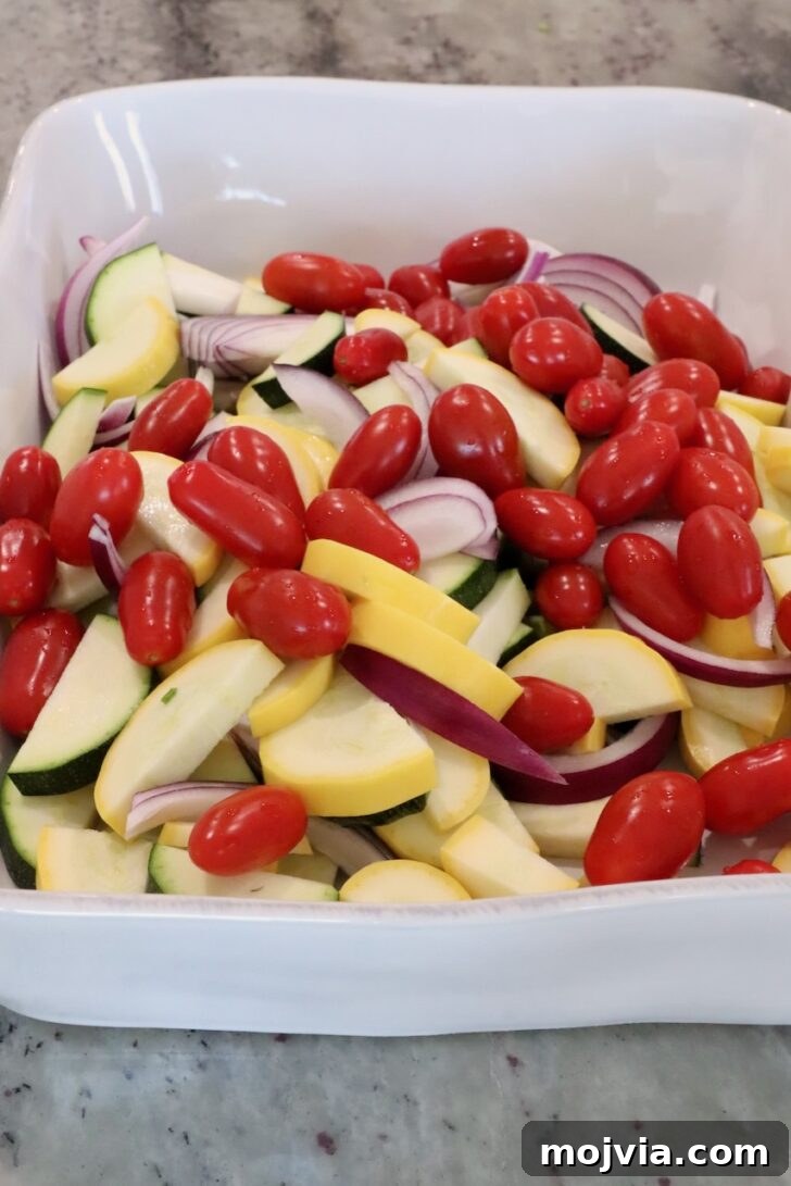 Creamy Boursin Pasta Primavera with Spring Vegetables 6 sliced yellow squash, zucchini, asparagus and onions in a large baking dish with cherry tomatoes