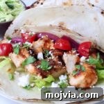 Chipotle Honey Chicken Tacos Made in the Air Fryer 12 air fryer chicken tacos topped with diced tomatoes, pickled onions, cilantro, lettuce, and crumbled cheese on lightly charred tortillas.