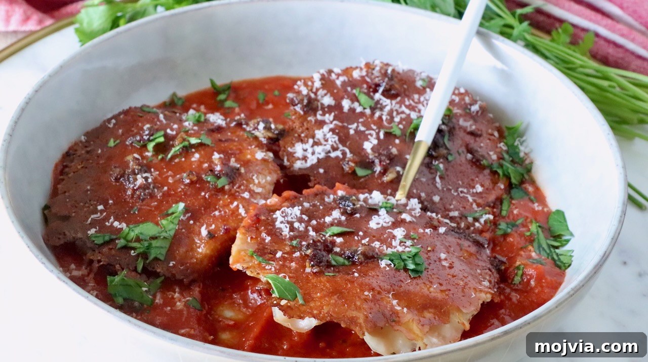 Calabrian Chili Crisp: Spicy Oil Recipe & Flavor Uses 12 chicken ravioli with a mozzarella cheese crust in a bowl of marinara sauce with a fork, topped with fresh parsley and parmesan cheese