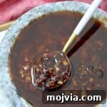 Calabrian Chili Crisp: Spicy Oil Recipe & Flavor Uses 13 Calabrian chili crisp in a gray bowl with a white and gold spoon dipped in the sauce