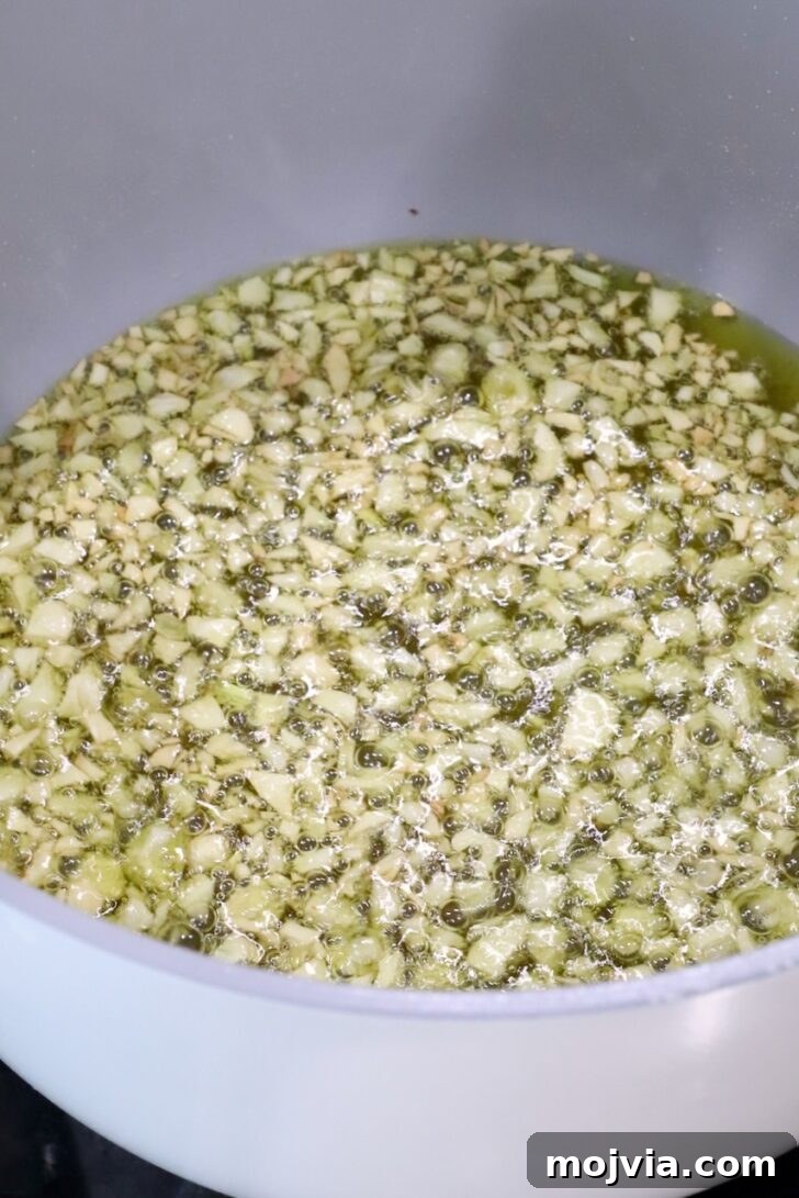 Calabrian Chili Crisp: Spicy Oil Recipe & Flavor Uses 8 pot of oil and minced garlic on the stove