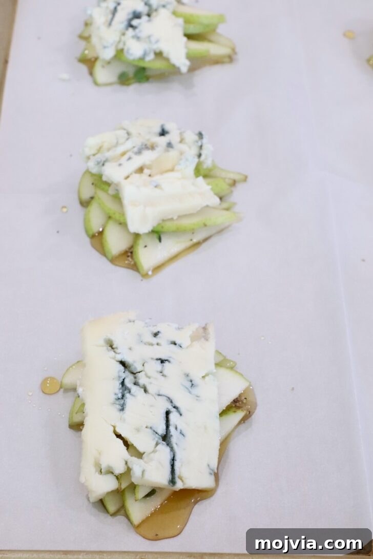 Gorgonzola and Pear Tart Recipe: Savory-Sweet Rustic Tart 11 slices of gorgonzola cheese on top of sliced pears and honey on a sheet of parchment paper on a baking sheet