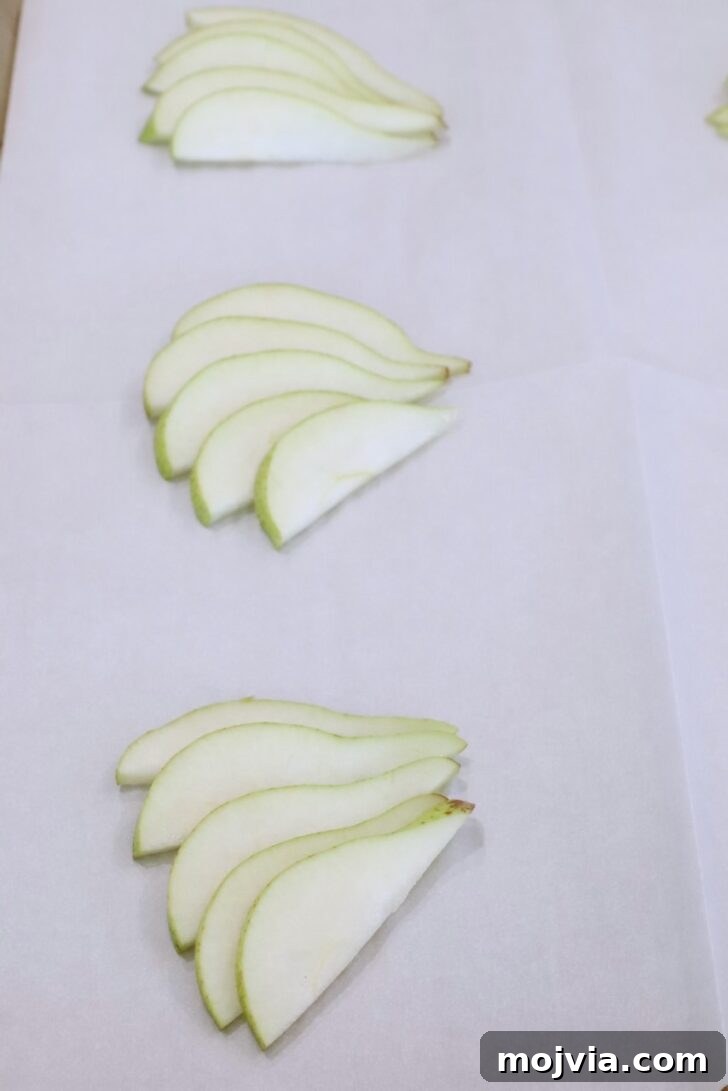 Gorgonzola and Pear Tart Recipe: Savory-Sweet Rustic Tart 7 sliced pears on a sheet of parchment paper on a baking sheet