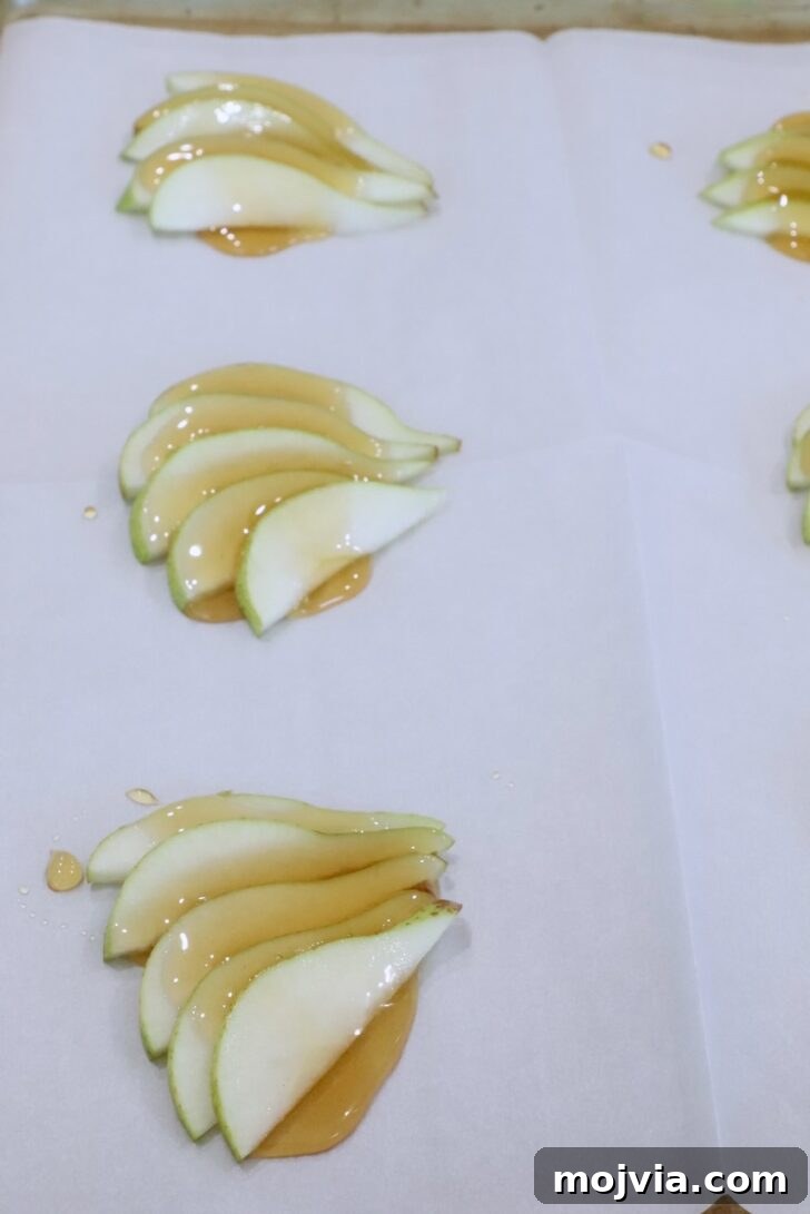 Gorgonzola and Pear Tart Recipe: Savory-Sweet Rustic Tart 8 sliced pears topped with honey on a sheet of parchment paper on a baking sheet
