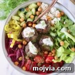 Greek Gyro Meatballs Recipe — Flavorful Mediterranean Meatballs 12 A colorful Mediterranean bowl with meatballs topped with yogurt sauce, surrounded by fresh lettuce, cherry tomatoes, cucumber, onions, and chickpeas.