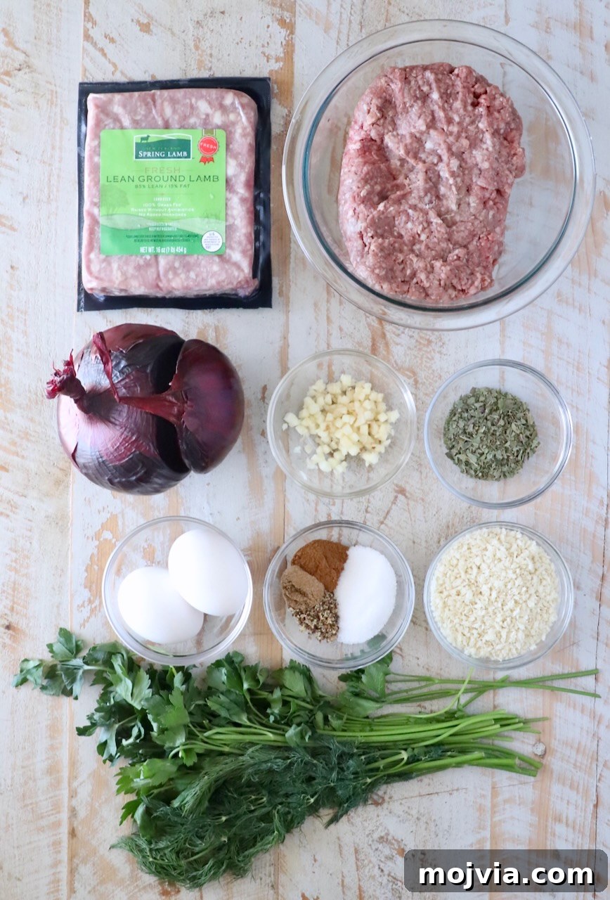Greek Gyro Meatballs Recipe — Flavorful Mediterranean Meatballs 5 Ingredients for gyro meatballs on wooden surface: packaged lean ground lamb, ground beef in a glass bowl, chopped garlic, dry herbs, eggs, spices, panko breadcrumbs, red onion, fresh parsley, and dill.