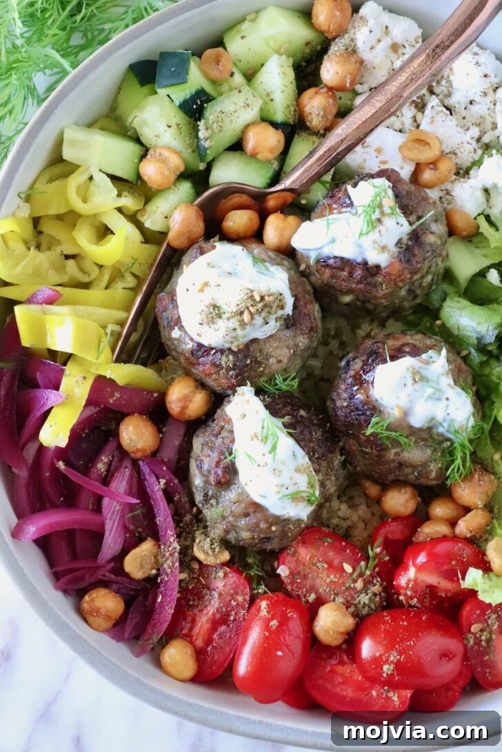Greek Gyro Meatballs Recipe — Flavorful Mediterranean Meatballs 10 bowl filled with gyro meatballs topped with tzatziki sauce, surrounded by cucumbers, tomatoes, pickled onions, and chickpeas