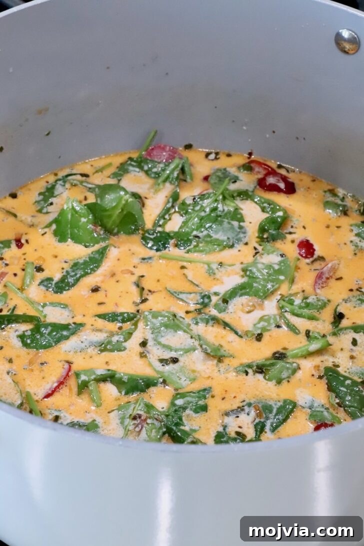 Creamy Tuscan Chicken Pasta Recipe with Sun-Dried Tomatoes 11 creamy tuscan sauce with spinach leaves and sun dried tomatoes in a sauce pan