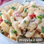 Creamy Tuscan Chicken Pasta Recipe with Sun-Dried Tomatoes 13 A bowl of creamy tuscan pasta topped with fresh parsley and grated cheese