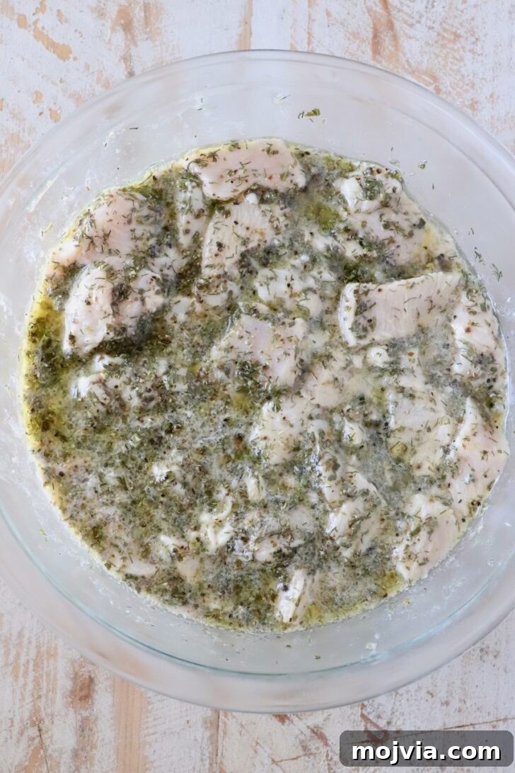 Authentic Greek Souvlaki Recipe: How to Make Classic Meat Skewers 6 cubes of raw chicken in a lemon herb marinade in a glass bowl