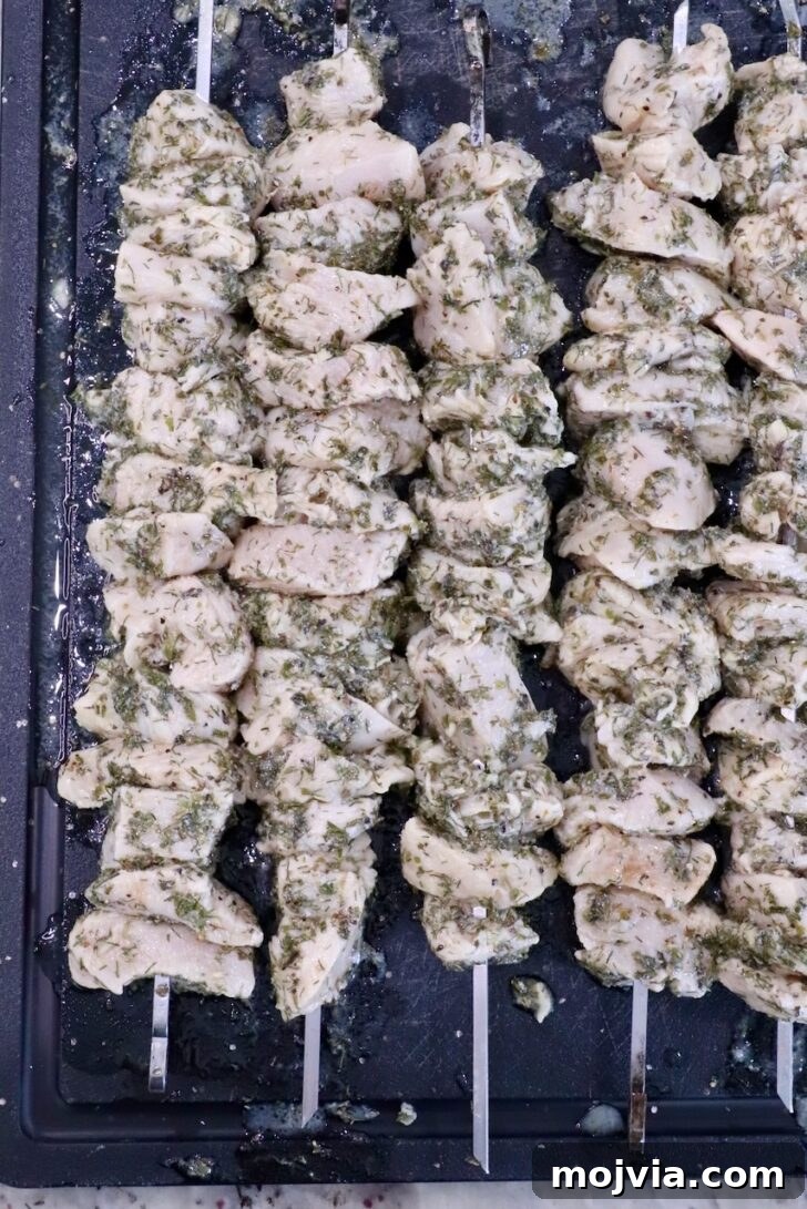 Authentic Greek Souvlaki Recipe: How to Make Classic Meat Skewers 7 skewered cubes of marinated chicken on a black cutting board