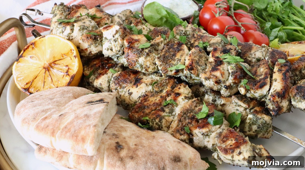 Authentic Greek Souvlaki Recipe: How to Make Classic Meat Skewers 10 grilled chicken skewers on a plate with pita bread, grilled lemons, tomatoes and herbs