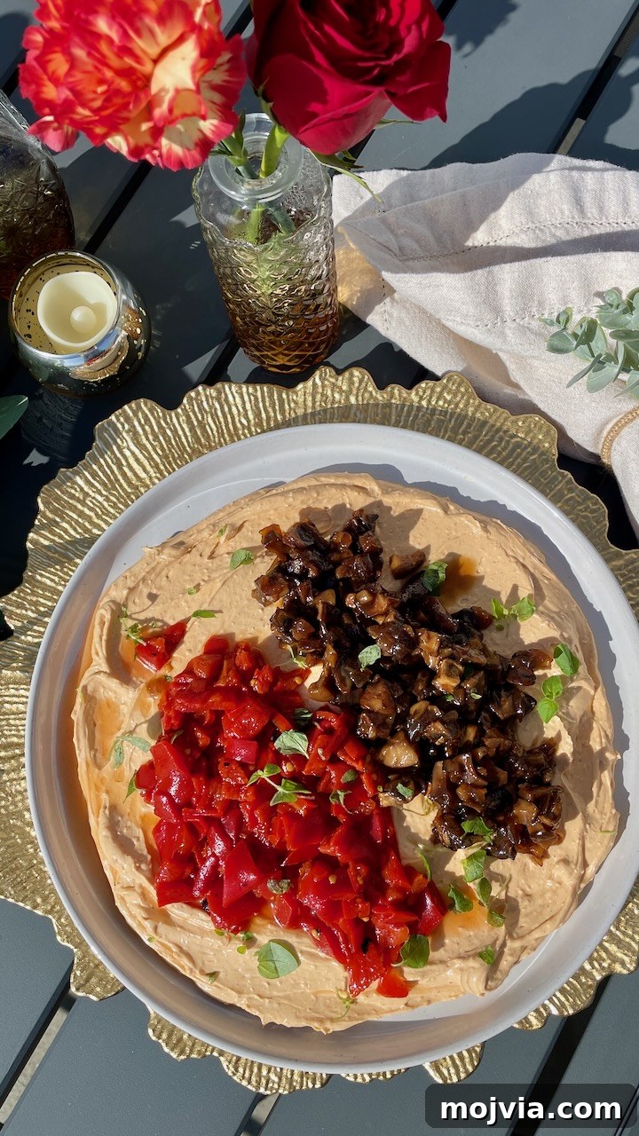 Savory Mushroom Jam Recipe for Spreading and Cooking 12 whipped goat cheese on a plate topped with mushroom jam and diced roasted peppers, with flowers and a candle on the side of the plate