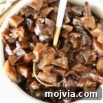 Savory Mushroom Jam Recipe for Spreading and Cooking 13 mushroom jam in a white bowl with a gold and white spoon